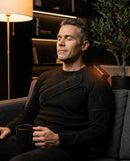 Man wearing the PyreFit heated shoulder wrap on the sofa