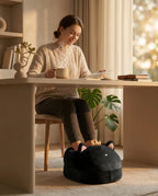 Woman using the cat-shaped sherpa foot warmer at her desk